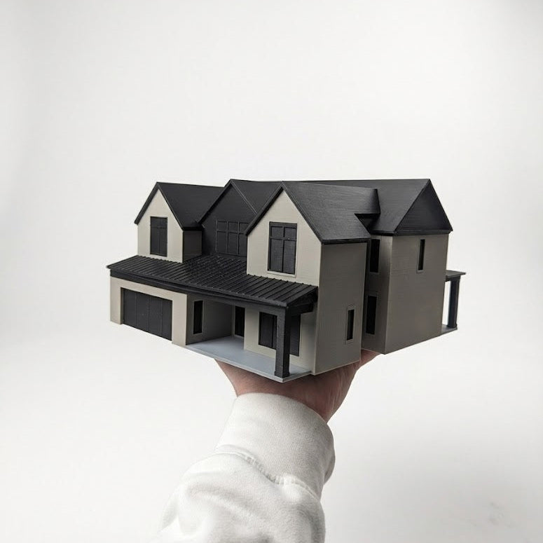 Hand holding a miniature model of a house against a white background